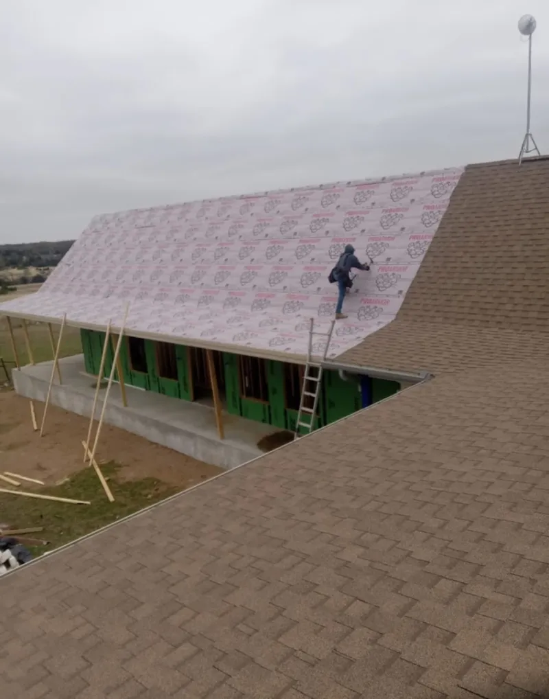 Worker preparing underlayment for a metal roof installation in Monroe